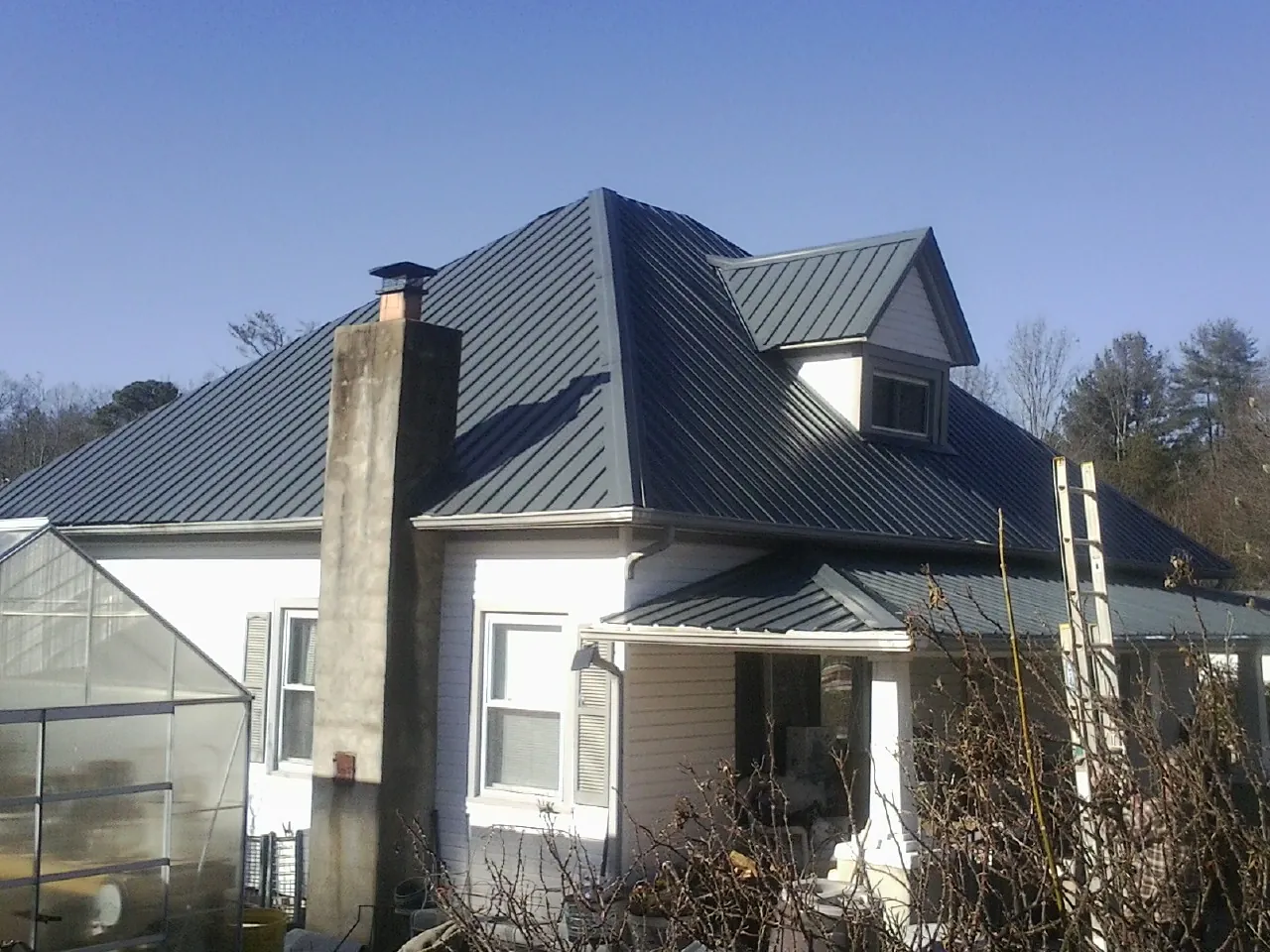 Dark blue standing seam metal roof on a white farmhouse with dormer — Slate & Tile Roof Repair by Roofing Brothers in Rapelje