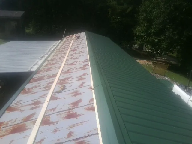 Old rusted panels beside newly installed green metal roofing — Wind Damage Roof Repair by Roofing Brothers in Rapelje