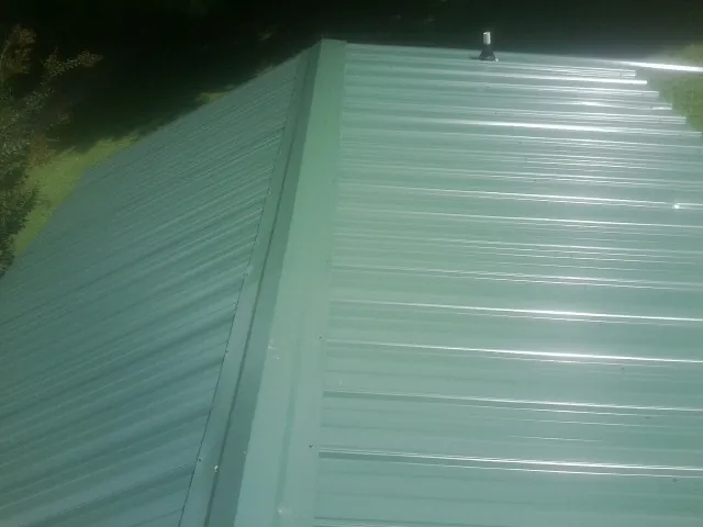 New green metal panels meeting at the ridge of a roof — Flat Roof Repair work by our crew in Rapelje