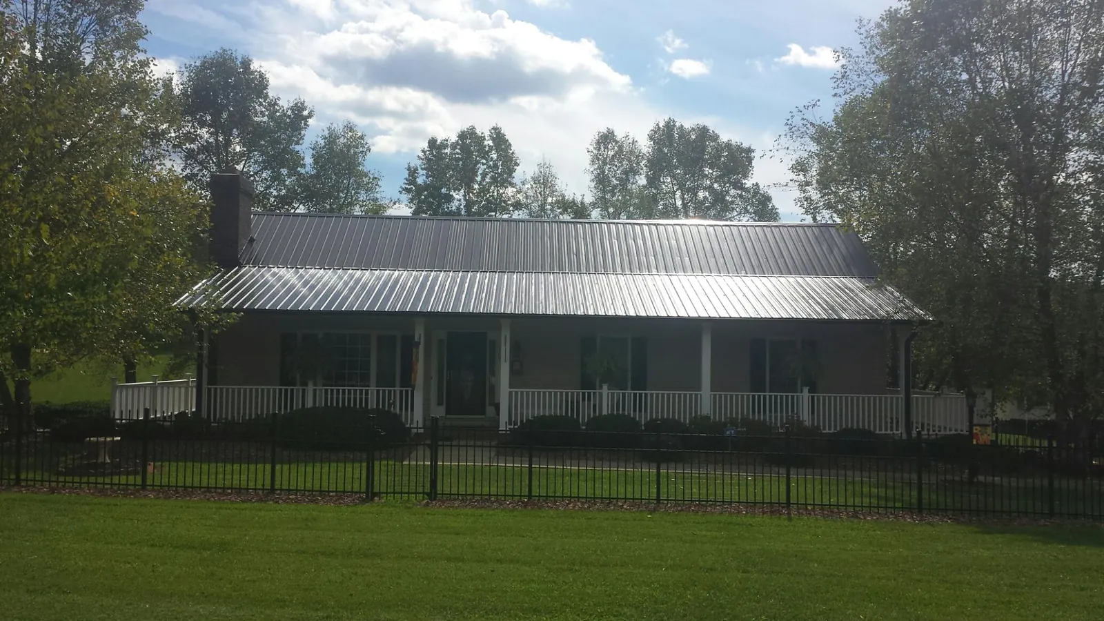 Gray metal roof on a brick ranch with a full width front porch — Gutter Guard Installation work by our crew in Rapelje