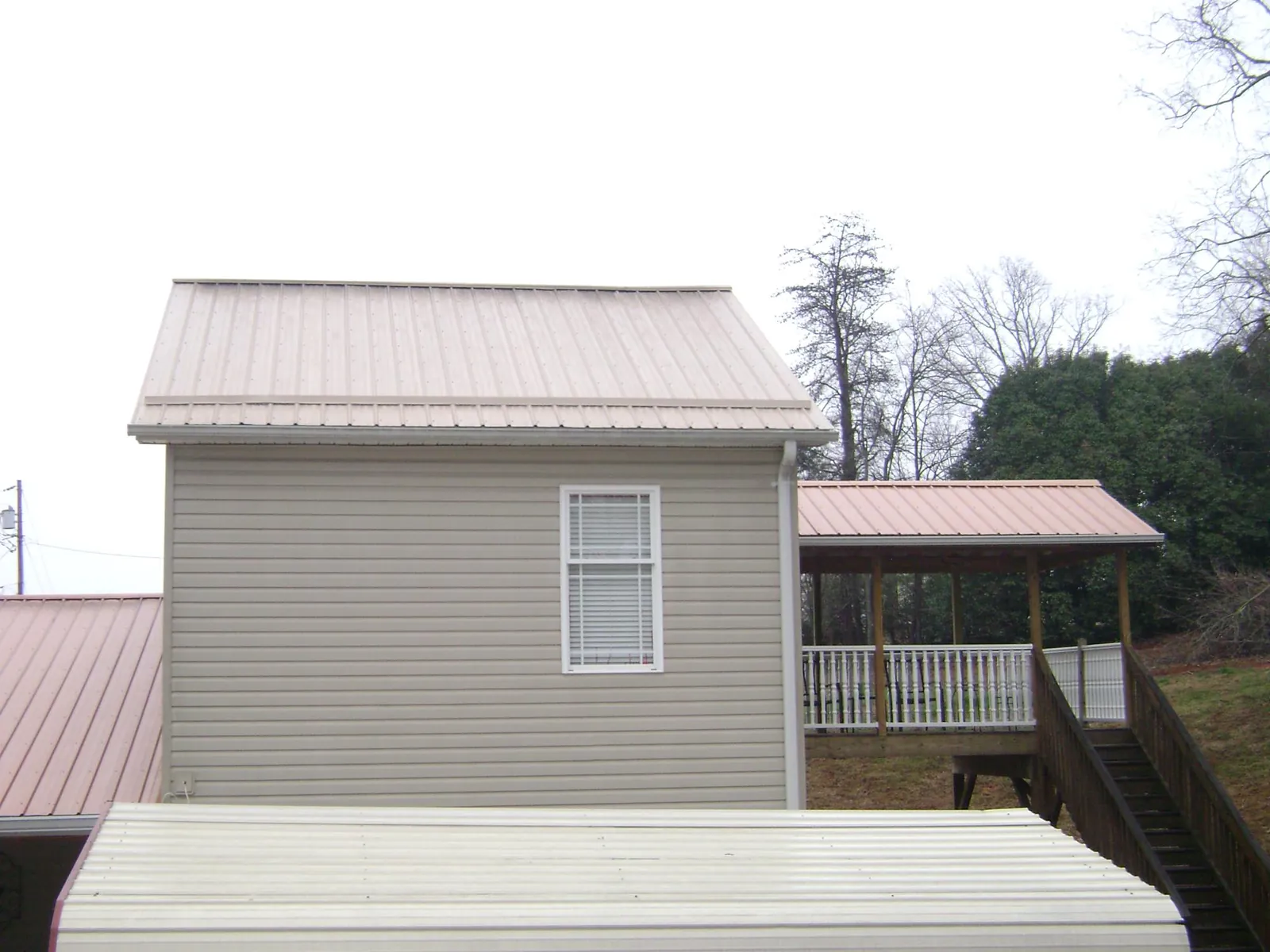 Tan metal roofs on a two story addition and attached porch, from a Roof Replacement job in Rapelje
