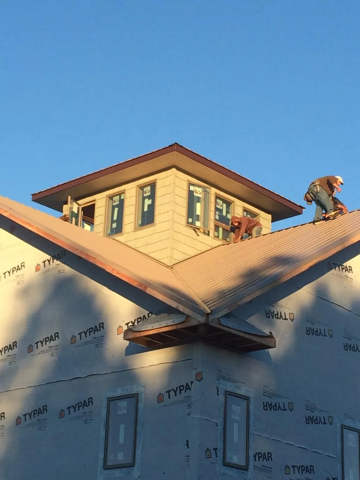 Roofers working around a rooftop cupola on a new metal roof at sunset — Roof Waterproofing in Rapelje by Roofing Brothers